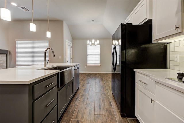 kitchen featuring white cabinets, black refrigerator, vaulted ceiling, an island with sink, and dark hardwood / wood-style flooring