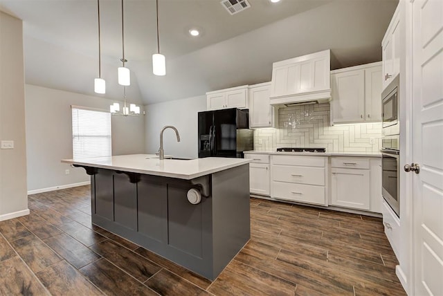 kitchen with lofted ceiling, dark wood-type flooring, a center island with sink, sink, and stainless steel appliances