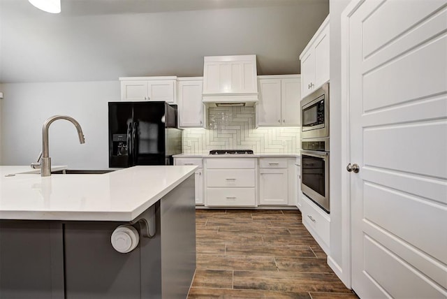 kitchen with sink, dark hardwood / wood-style floors, decorative backsplash, appliances with stainless steel finishes, and white cabinetry