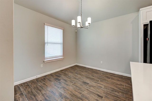 spare room featuring dark hardwood / wood-style flooring and a notable chandelier