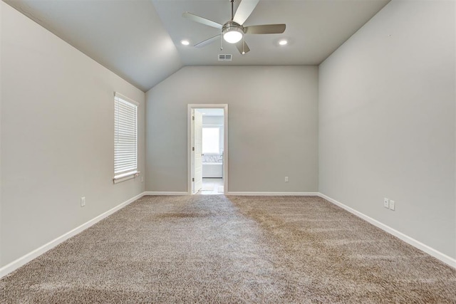 carpeted spare room with ceiling fan and vaulted ceiling