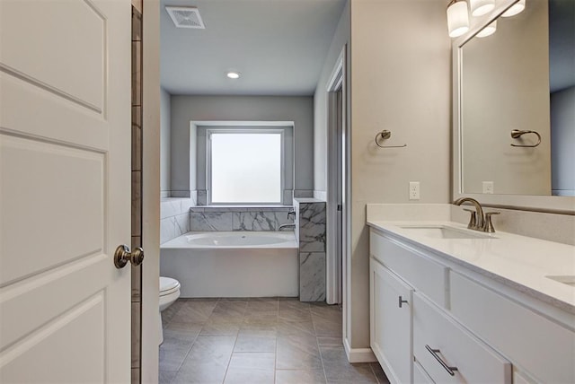 bathroom featuring tile patterned flooring, vanity, a tub to relax in, and toilet