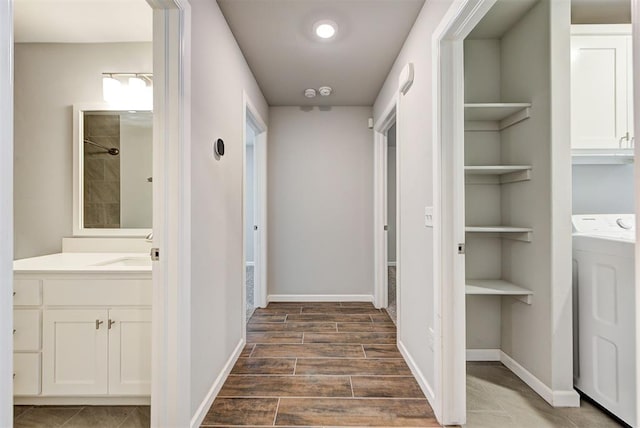 corridor with sink, dark hardwood / wood-style flooring, built in features, and washer / dryer