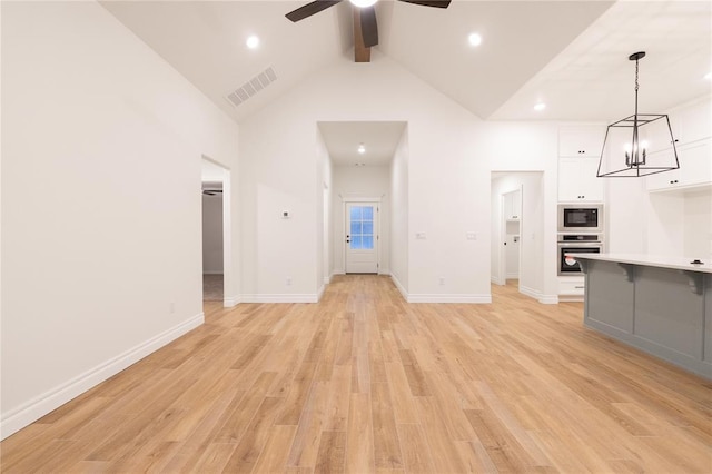 9216 NW 117th St, Yukon, OK 73099 - unfurnished living room featuring a ceiling fan, beam ceiling, high vaulted ceiling, light wood finished floors, and a chandelier