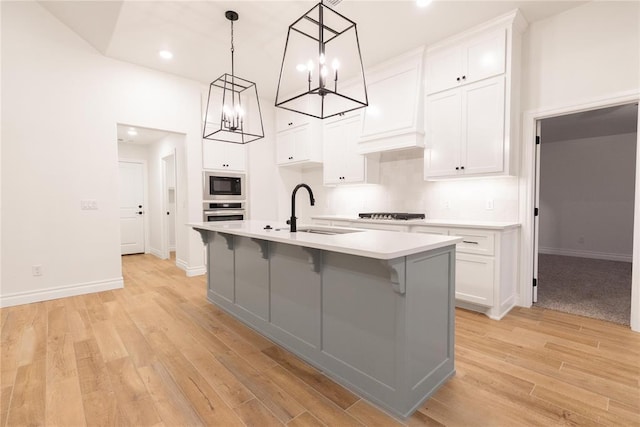 9216 NW 117th St, Yukon, OK 73099 - kitchen with a sink, black microwave, a chandelier, stainless steel oven, and light wood-type flooring