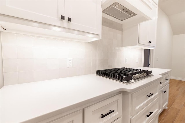 9216 NW 117th St, Yukon, OK 73099 - kitchen featuring stainless steel gas cooktop, light countertops, range hood, white cabinets, and tasteful backsplash