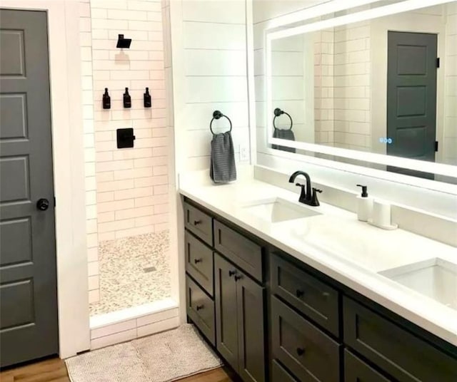 bathroom featuring hardwood / wood-style flooring, vanity, and tiled shower