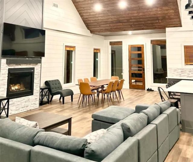 living room featuring a fireplace, high vaulted ceiling, and light hardwood / wood-style floors