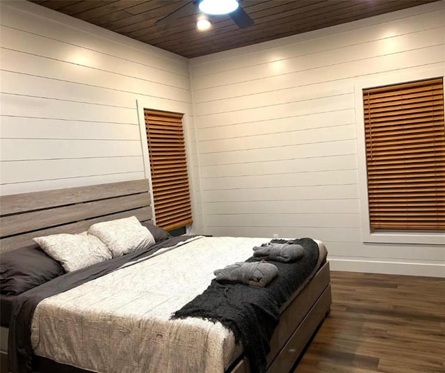 bedroom featuring dark hardwood / wood-style floors, ceiling fan, wood ceiling, and wooden walls