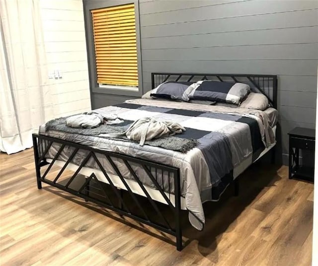 bedroom featuring wooden walls and wood-type flooring