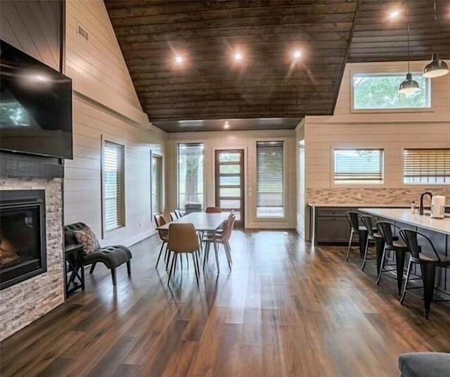 dining area with a fireplace, dark hardwood / wood-style flooring, high vaulted ceiling, and a wealth of natural light