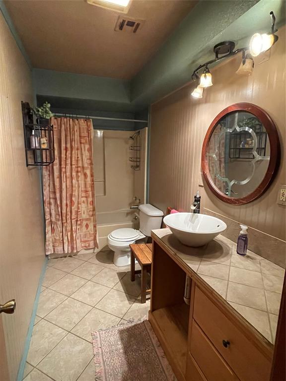 full bathroom with tile patterned flooring, vanity, toilet, and shower / bath combo with shower curtain