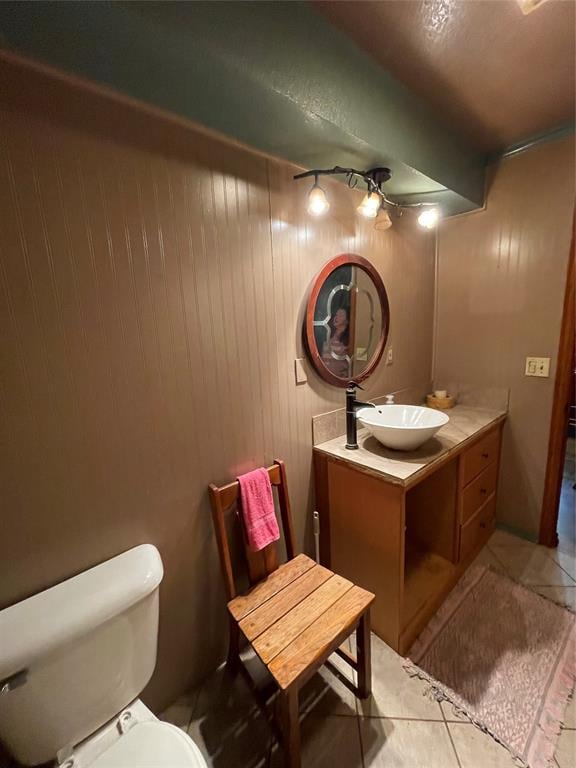 bathroom featuring vanity, tile patterned floors, wooden walls, ceiling fan, and toilet