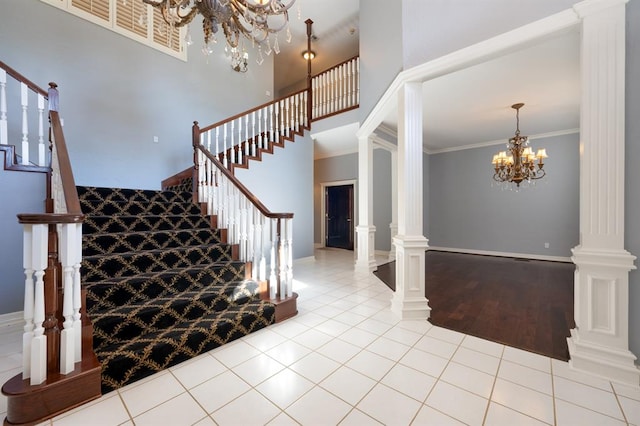 stairway with decorative columns, ornamental molding, hardwood / wood-style flooring, a notable chandelier, and a high ceiling