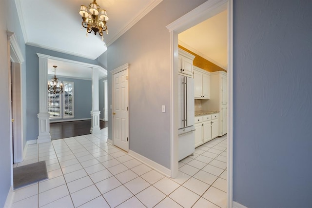 hall with decorative columns, ornamental molding, light tile patterned floors, and an inviting chandelier