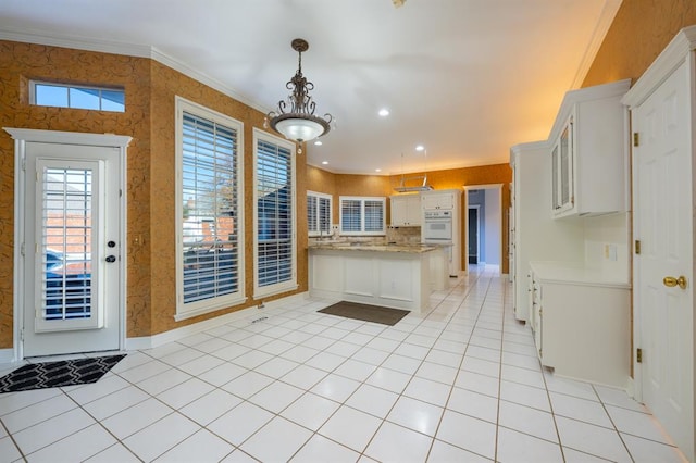 kitchen with white cabinets, kitchen peninsula, hanging light fixtures, and ornamental molding