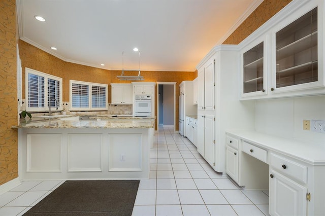 kitchen featuring light stone countertops, ornamental molding, sink, light tile patterned floors, and white cabinets