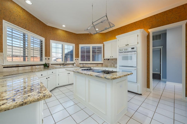 kitchen featuring light stone countertops, ornamental molding, sink, white cabinets, and a kitchen island