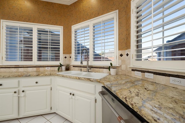 kitchen featuring white cabinetry, sink, stainless steel dishwasher, crown molding, and light tile patterned flooring