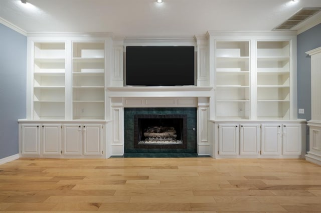 unfurnished living room featuring a tile fireplace, light wood-type flooring, and ornamental molding