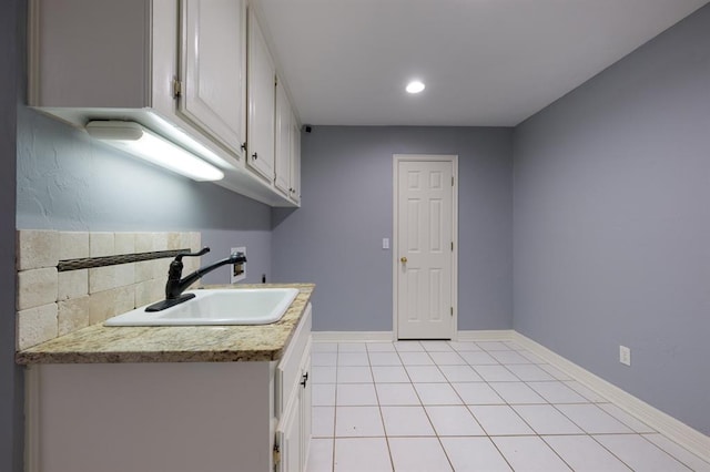 kitchen with light tile patterned flooring, backsplash, white cabinetry, and sink