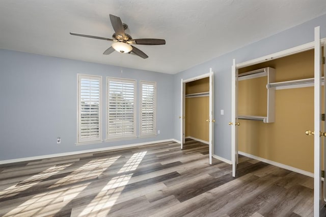 unfurnished bedroom with multiple closets, ceiling fan, and dark hardwood / wood-style flooring