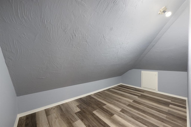 bonus room with a textured ceiling, wood-type flooring, and vaulted ceiling