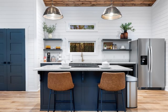 bar featuring pendant lighting, sink, stainless steel refrigerator with ice dispenser, light wood-type flooring, and light stone counters