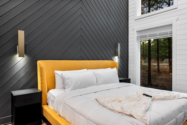 bedroom featuring wood walls, a towering ceiling, and access to outside