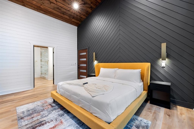 bedroom featuring wood walls, high vaulted ceiling, ensuite bath, light wood-type flooring, and wood ceiling