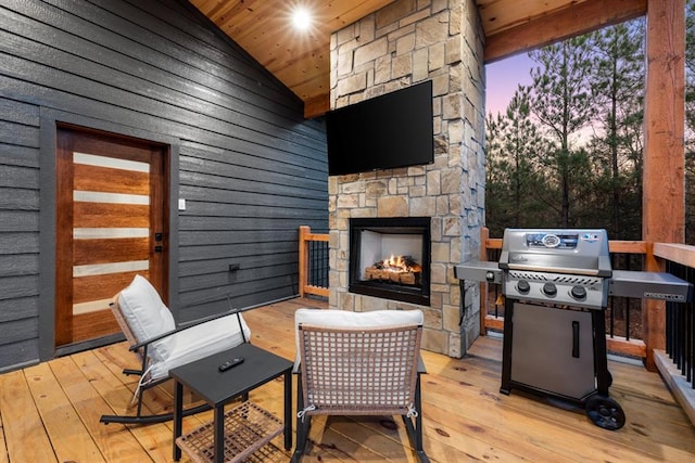 wooden terrace featuring an outdoor stone fireplace and grilling area