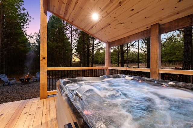 deck at dusk featuring a hot tub