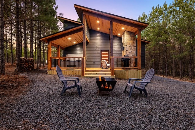 back house at dusk featuring a fire pit and a wooden deck