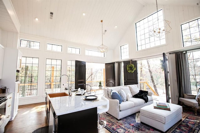 living room featuring sink, dark hardwood / wood-style flooring, high vaulted ceiling, and a notable chandelier