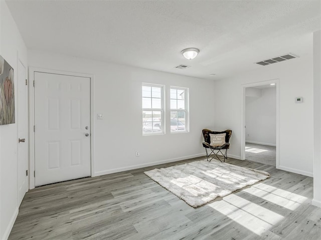 foyer entrance with a textured ceiling and light hardwood / wood-style flooring