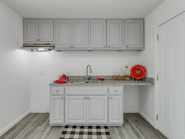 kitchen featuring a textured ceiling, light hardwood / wood-style floors, and sink