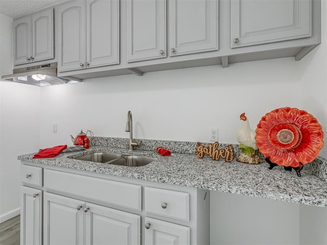 kitchen featuring light stone countertops, sink, a textured ceiling, and hardwood / wood-style flooring