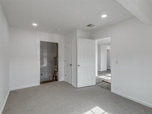 unfurnished bedroom with light colored carpet and a closet