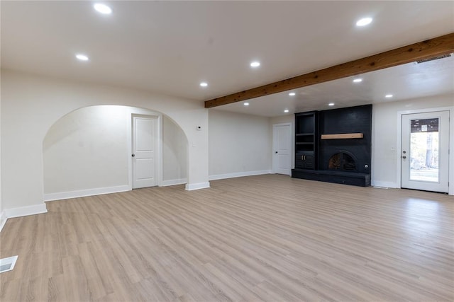 unfurnished living room with a large fireplace, light hardwood / wood-style flooring, and beam ceiling