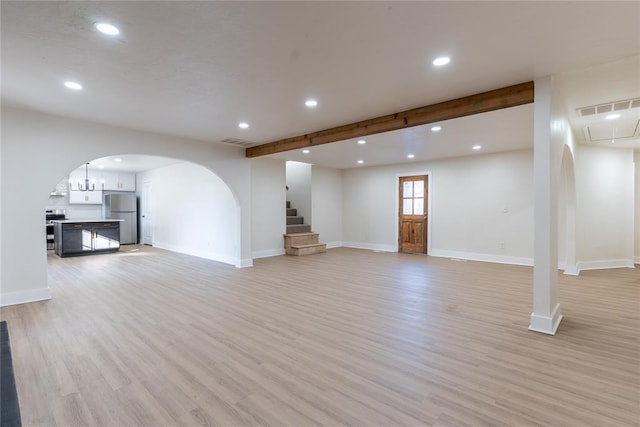 unfurnished living room featuring beamed ceiling and light hardwood / wood-style floors