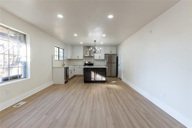 kitchen featuring light hardwood / wood-style floors, white cabinetry, stainless steel appliances, and a wealth of natural light