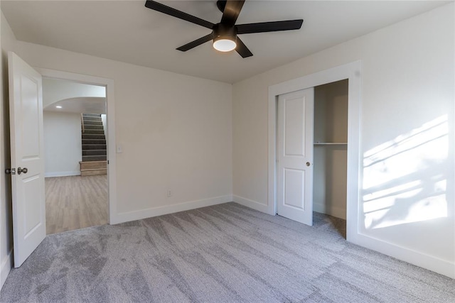 unfurnished bedroom with ceiling fan, light colored carpet, and a closet