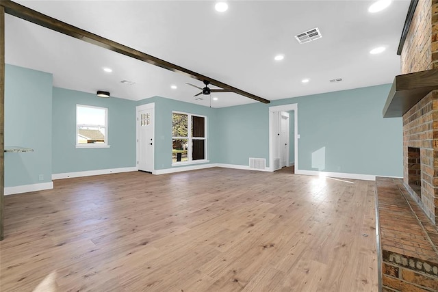 unfurnished living room featuring beam ceiling, ceiling fan, a fireplace, and light hardwood / wood-style flooring