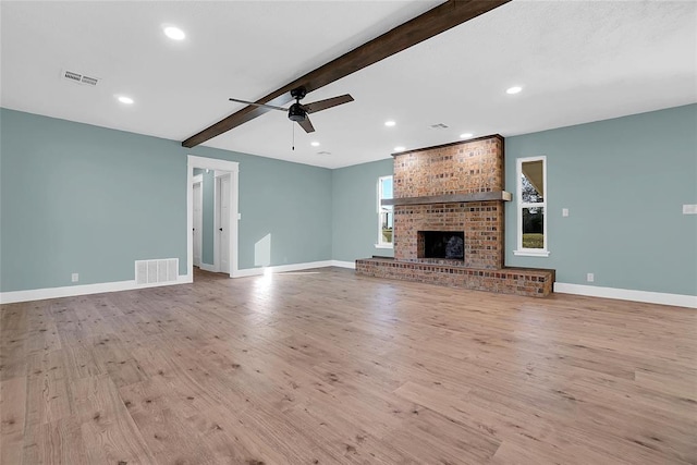 unfurnished living room with beamed ceiling, ceiling fan, light wood-type flooring, and a fireplace