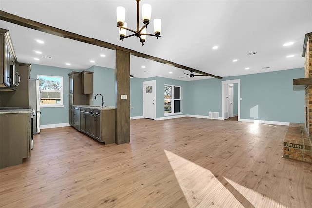 kitchen with ceiling fan with notable chandelier, sink, light hardwood / wood-style flooring, light stone countertops, and stainless steel appliances