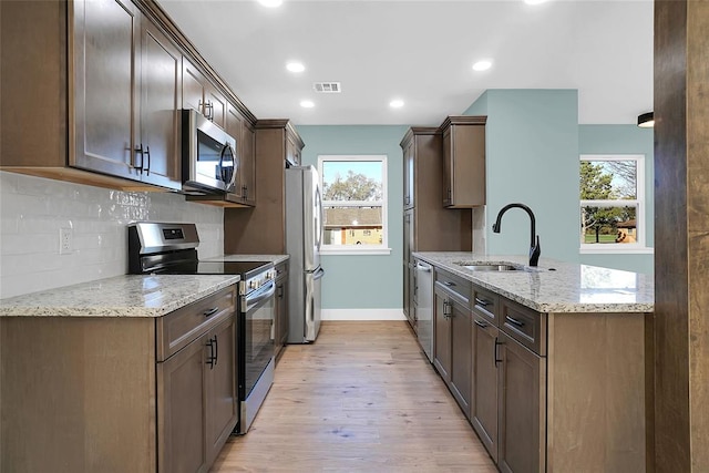 kitchen with plenty of natural light, sink, stainless steel appliances, and light hardwood / wood-style flooring