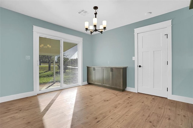 unfurnished dining area with an inviting chandelier and light hardwood / wood-style flooring