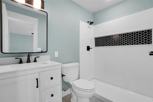 bathroom with tile patterned floors, vanity, toilet, and tiled shower