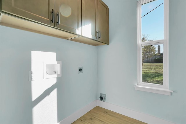 laundry area with hookup for an electric dryer, washer hookup, light hardwood / wood-style floors, and cabinets