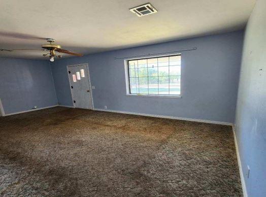 spare room with dark carpet and ceiling fan